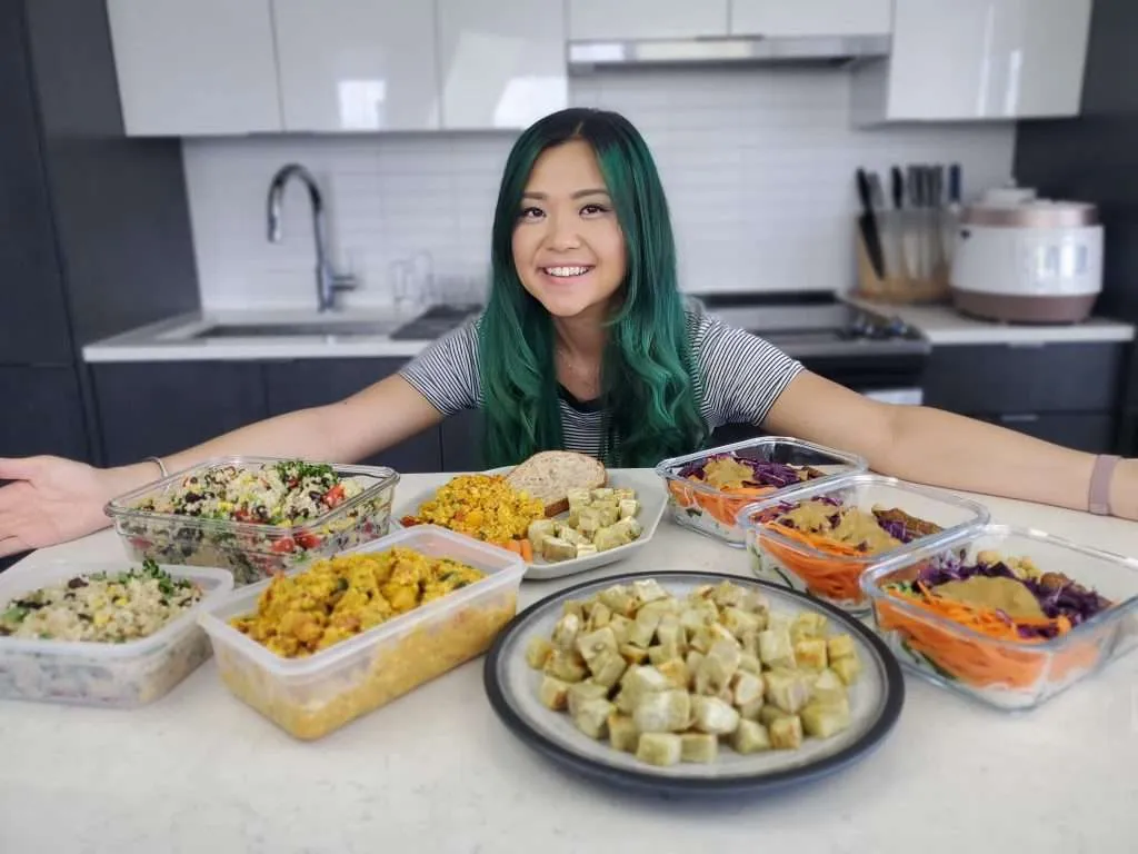 Rose smiling behind the plates of the high protein vegan meal prep recipes she made
